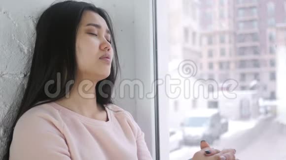 年轻的亚洲女人睡在窗前视频的预览图