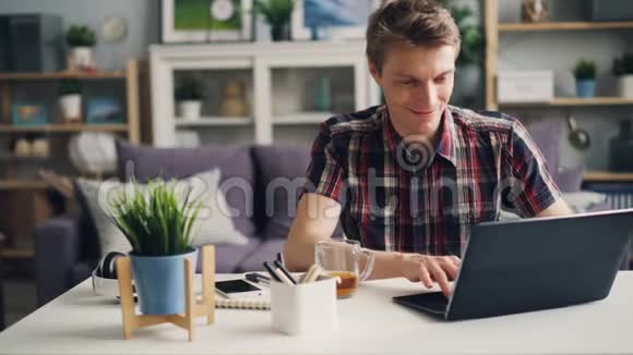 快乐的自雇人士正在家工作用笔记本电脑微笑和欢笑享受他的成就现代视频的预览图