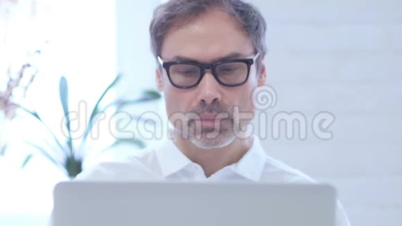 在笔记本电脑上工作的时候一个震惊的中年男人正在思考视频的预览图