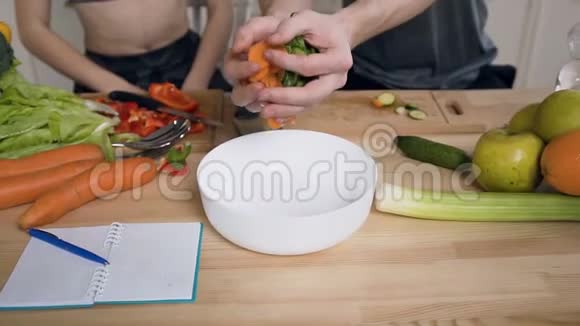 男人他的手放着切碎的新鲜胡萝卜和黄瓜用蔬菜和油做新鲜的夏季沙拉视频的预览图