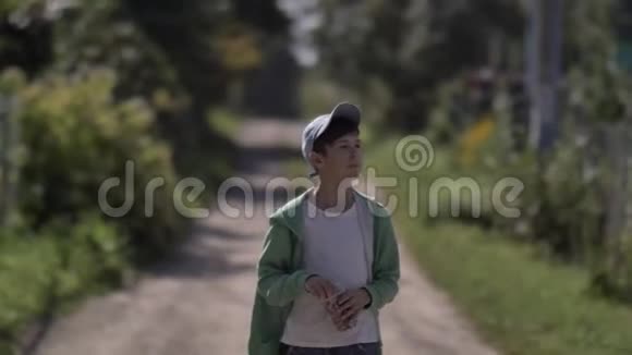 男孩走在乡间小路上在户外吃爆米花视频的预览图