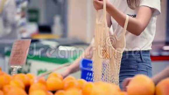 漂亮的女孩子在超市里用网状有机购物袋摘蔬菜和水果零浪费环保视频的预览图