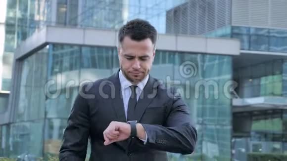 商务人士使用智能手表步行至办公室视频的预览图