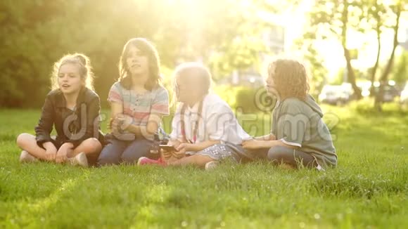 学校休息时快乐的小学生坐在公园的一片空地上孩子们扔草回到学校视频的预览图