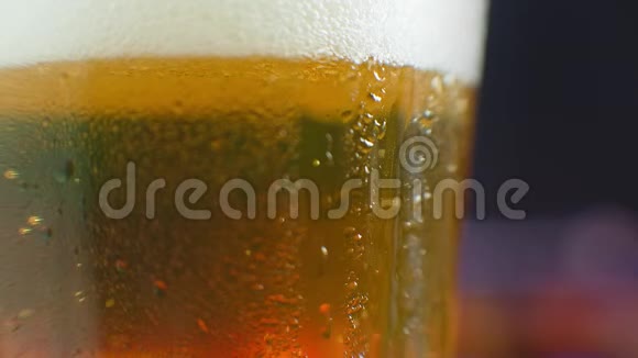 从一杯啤酒上掉了一滴水在一杯冰冷的啤酒上流汗一滴滴在玻璃上视频的预览图