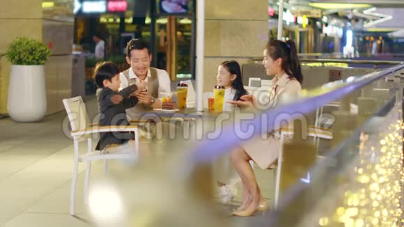 有两个孩子的亚洲家庭在咖啡店放松视频的预览图