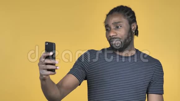黄色背景下手机自拍的非洲休闲男子视频的预览图