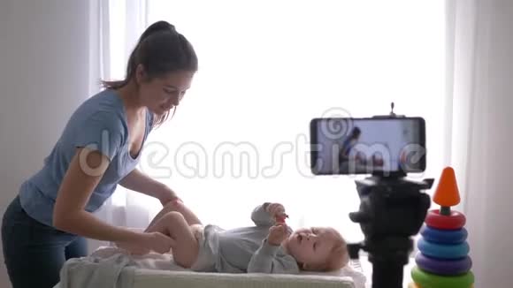 孕产妇保健著名博主妈妈在手机上录制视频课时给婴儿换衣服视频的预览图