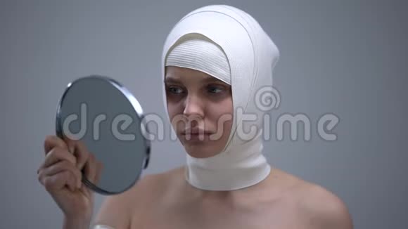女性穿弹性头巾照镜子整容后感觉疼痛视频的预览图