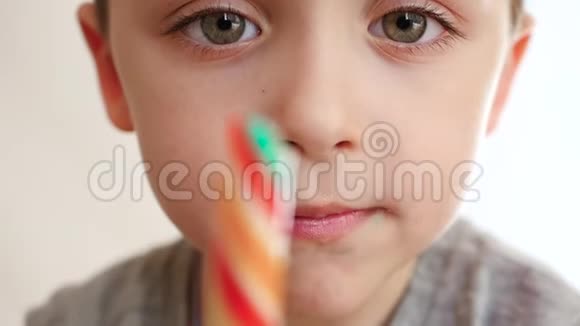 学龄前儿童肖像一个可爱的小男孩张开嘴吃一个女士糖果特写视频的预览图
