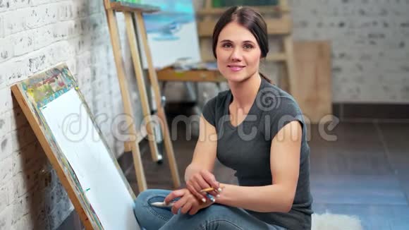 微笑的艺术家的肖像妇女摆在艺术工作室看相机中镜头视频的预览图