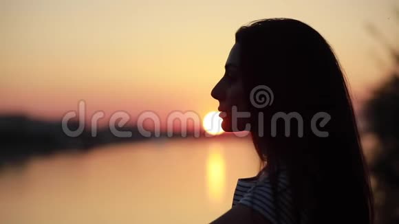 女人放松和看日落的剪影视频的预览图