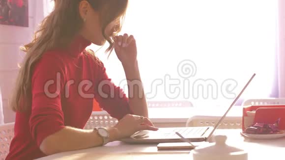 一个身穿红色连衣裙的金发女孩坐在笔记本电脑旁视频的预览图