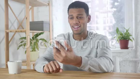 美国年轻男子在办公室的智能手机视频聊天视频的预览图