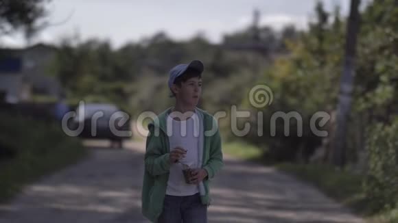 男孩走在乡间小路上在户外吃爆米花视频的预览图