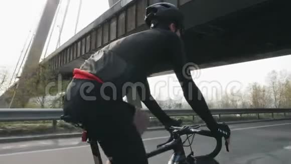 瘦瘦的骑自行车的人骑自行车在桥下后面跟着骑自行车的人在路上骑自行车视频的预览图