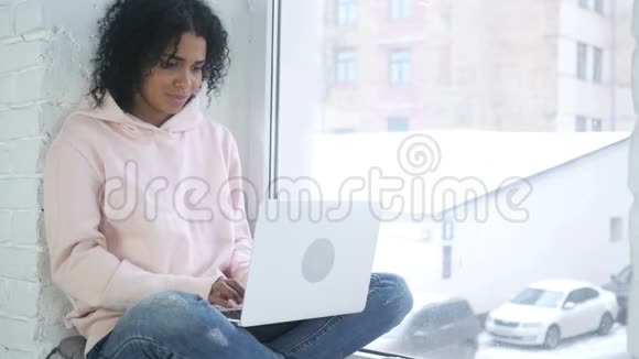 坐在窗边的美国黑人妇女在线视频聊天视频的预览图