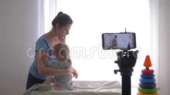 宝宝护理快乐博主妈妈在手机上录制训练视频时给小男孩换衣服视频的预览图
