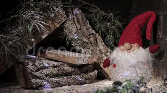 童话般的侏儒戴着圣诞红帽在木屋的背景上闪烁着灯光圣诞及新年作文视频的预览图