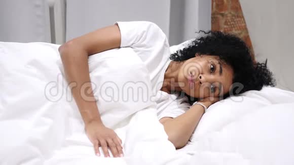 思考忧郁的美国女人躺在一边在床上做梦视频的预览图