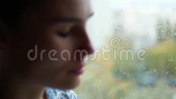 女人流鼻涕一个小女孩坐在窗边外面在下雨抑郁视频的预览图