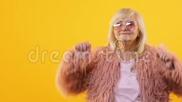 快乐的老年女性在黄色背景下慢动作跳舞感受年轻的派对视频的预览图