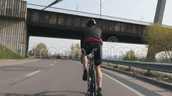 骑自行车的男性骑自行车后面跟着射击骑自行车的人穿着黑色和红色的衣服头盔和眼镜强壮的腿部肌肉视频的预览图