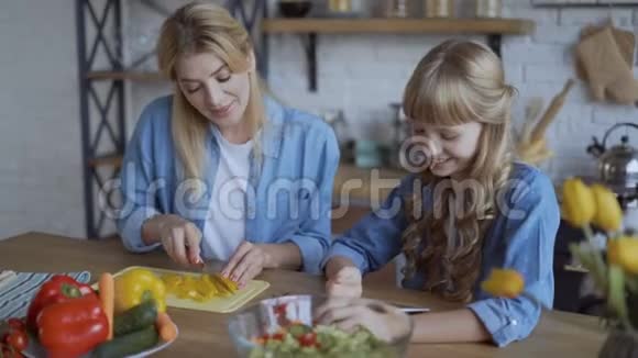妈妈和女儿一起在厨房做饭看着网上的菜谱手机平板电脑4K视频的预览图
