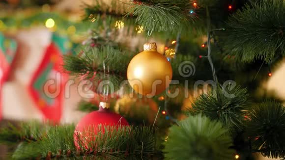 特写4k视频金色宝珠挂在圣诞树树枝上闪烁发光的圣诞灯花环上视频的预览图