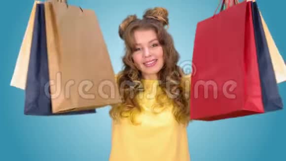 美丽的年轻女孩购物后摆着摆着包裹旋转和微笑同时看着相机视频的预览图