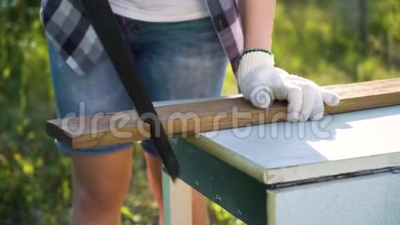 在阳光明媚的果园里女工用手锯木木板视频的预览图