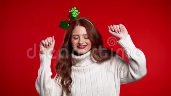 年轻女子在红棚背景下跳舞头戴圣诞花环的女孩视频的预览图