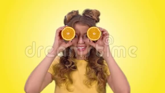 漂亮的女孩穿着一件黄色衬衫摆着橘子一边看着摄像机一边微笑着视频的预览图