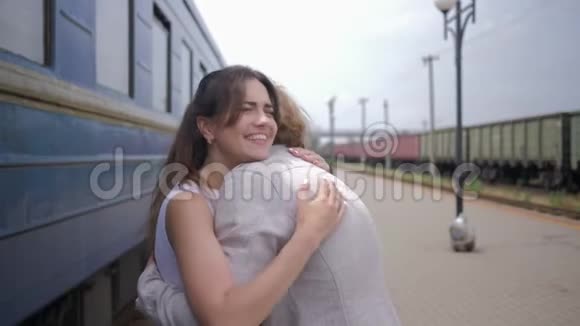 分手后幸福的相遇快乐的年轻女子拥抱男人在火车车厢旁欢笑视频的预览图