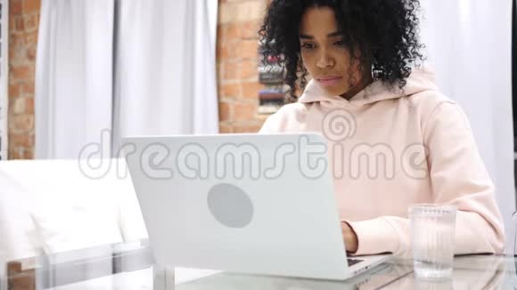 美国黑人妇女从玻璃上喝水和在笔记本电脑上工作的肖像视频的预览图