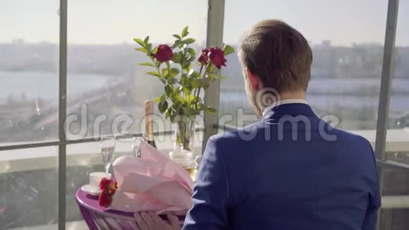 屋顶上的餐厅桌上放着令人惊叹的威耶夫河穿西装的男人坐在这张桌子上拿着玫瑰等着他的女人视频的预览图