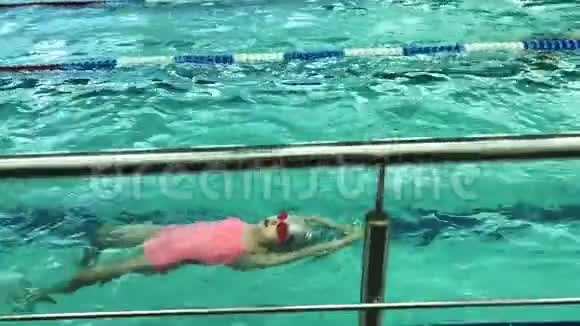 戴着游泳眼镜的女孩背在游泳池里游泳运动宝宝视频的预览图