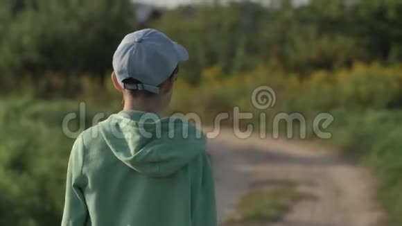 一个戴帽子的男孩在户外的乡间小路上散步视频的预览图