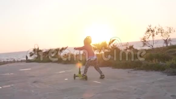 一个小女孩骑着滑板车沿着大海视频的预览图
