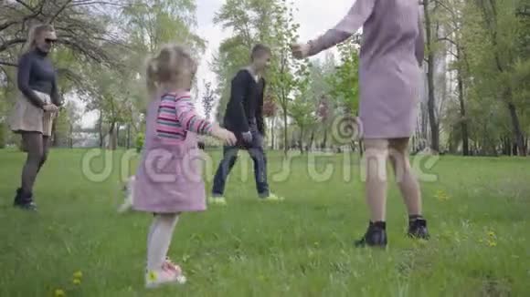 两个可爱的妈妈在春天的时候和他们的孩子在绿色神奇的公园里玩妈妈和儿子女儿在玩视频的预览图