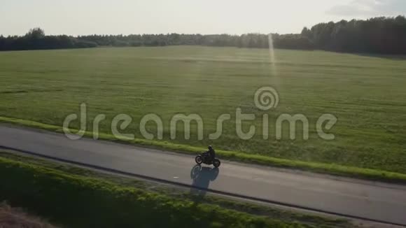 男子骑摩托车在日落乡村公路空中电子跟踪射击4K视频的预览图