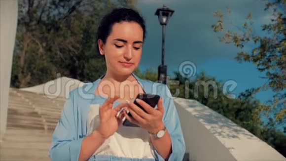 漂亮女人布鲁内特在蓝色西装与使用手机商务女性使用手机视频的预览图