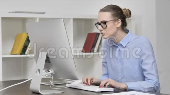 颈部疼痛的少女在电脑上工作视频的预览图