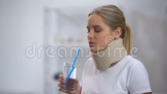 女孩在泡沫颈项圈试图喝玻璃水与稻草可怜的尝试视频的预览图