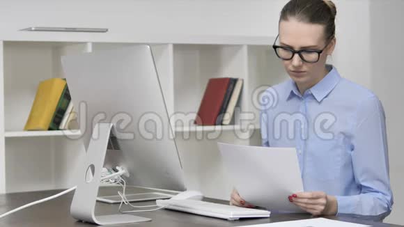 工作中穿着便服的年轻女孩阅读合同文书视频的预览图