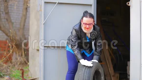 一个戴眼镜的女人正在从车库里拿出一个带圆盘的汽车轮胎视频的预览图