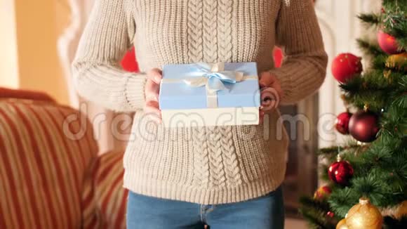 特写4k镜头年轻女子拿着圣诞礼物在盒子里与丝带弓并显示在相机家庭捐赠视频的预览图