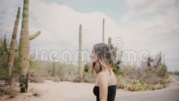镜头跟随年轻美丽的快乐旅游妇女头发随风飘向阳光明媚的仙人掌沙漠公园美国视频的预览图