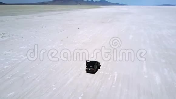 惊险的空中拍摄兴奋的夫妇走出微型面包车享受博纳维尔盐湖沙漠景观视频的预览图
