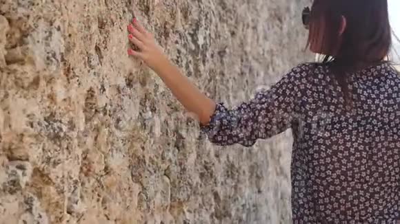 年轻女子触摸古墙视频的预览图